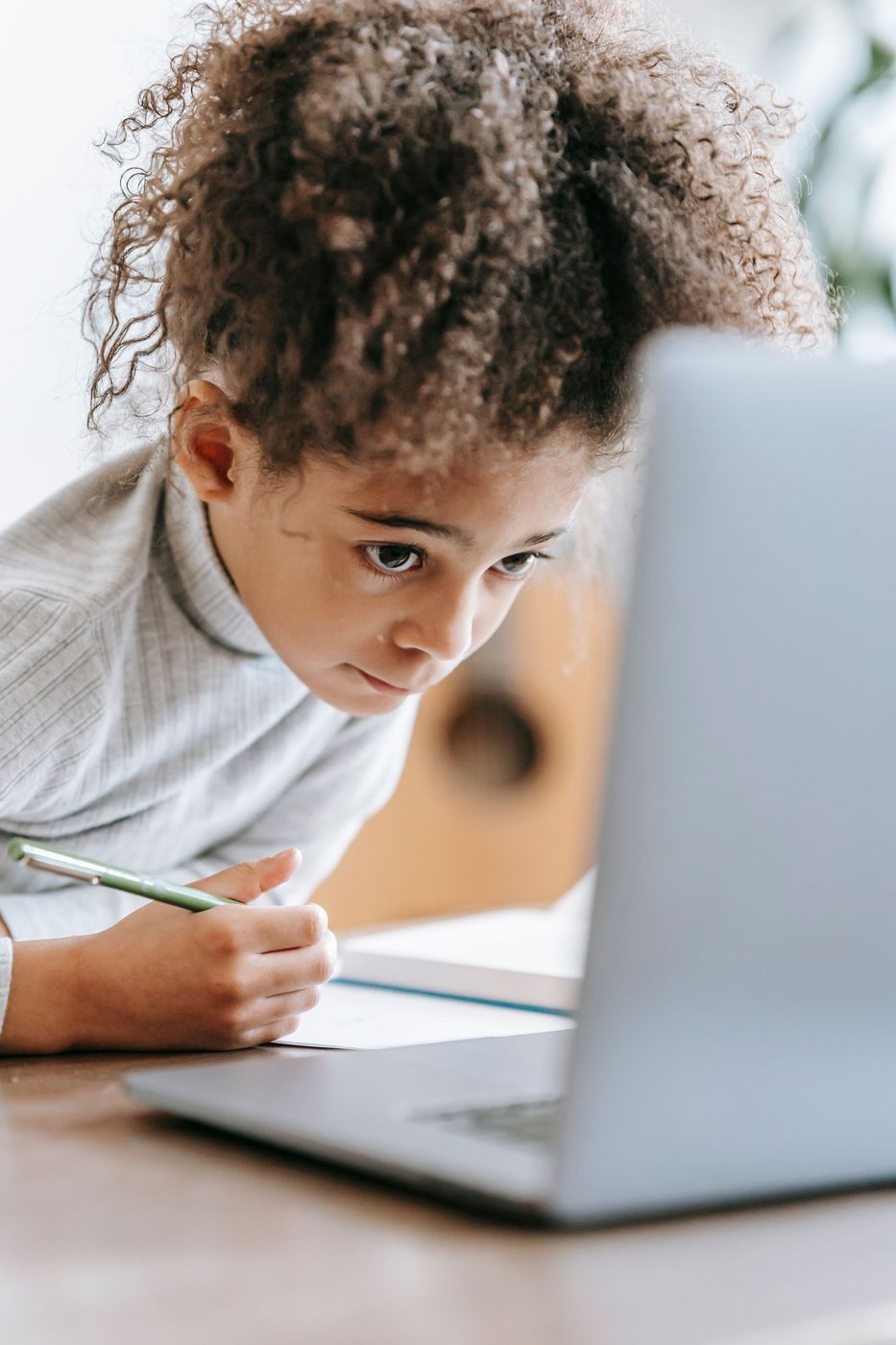 Year 6 pupil taking notes beside a laptop